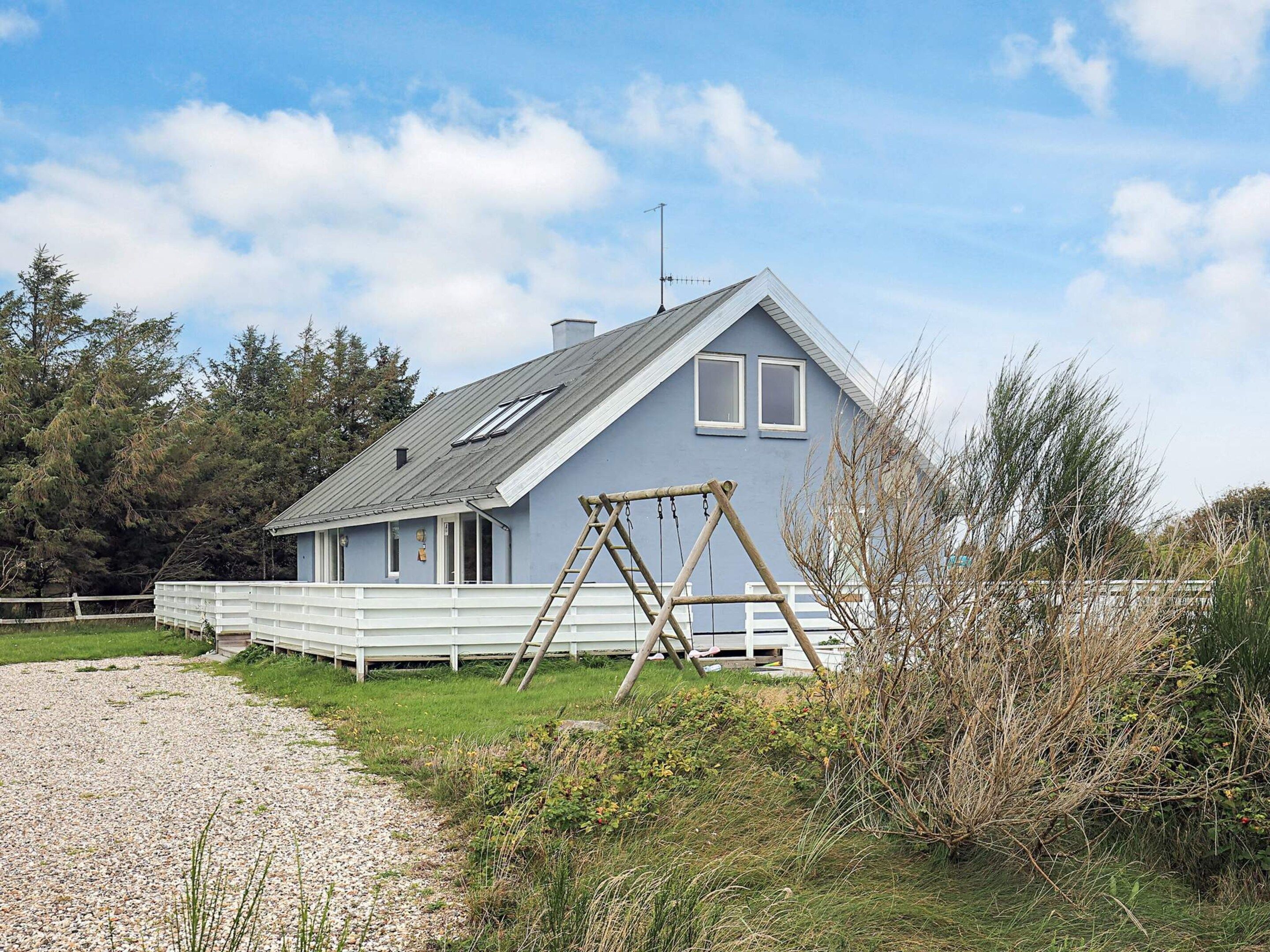 Een gelijkvloers huis met een puntige dakkapel, een veranda en een schommel.