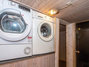 A laundry room with two washing machines, a wooden ceiling, and a door leading to another room. - 4 Star Holiday Home in Vestervig (Vestervig)