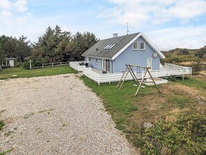A single-story house with a porch, a swing set, and a gravel driveway. - 4 Star Holiday Home in Vestervig (Vestervig)