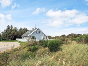 A single-story house with a sloped roof, a fenced yard, and a gravel driveway. - 4 Star Holiday Home in Vestervig (Vestervig)