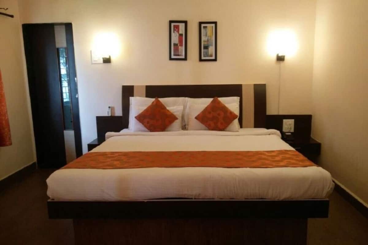 Ein Hotelzimmer mit einem großen Bett, zwei Nachttischlampen und zwei gerahmten Bildern an der Wand.
