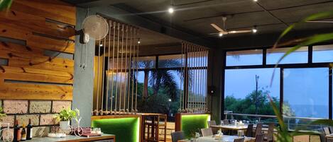 A restaurant with indoor seating, a bar area, and a view of the outdoors.
