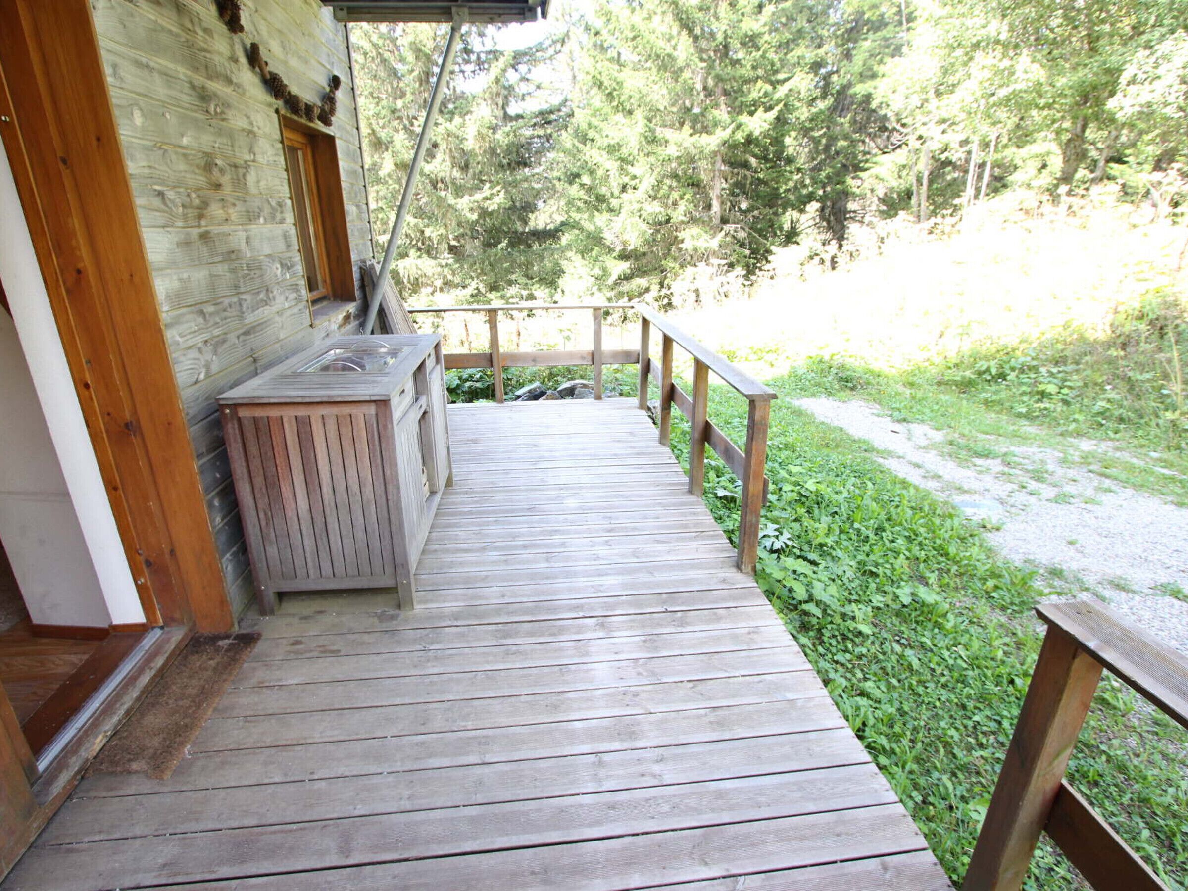 A wooden deck leading to a cabin with a built-in wood stove.