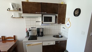 Cocina compacta con microondas, cafetera, lavaplatos y fregadero.