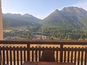A mountain view from a balcony with a wooden railing.