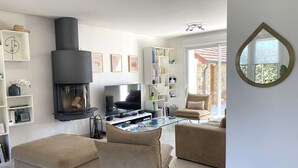 A modern living room with a fireplace, a flat-screen TV, a glass coffee table, and comfortable seating. - Contemporary villa 100m from the beach with garden and WIFI (Trégastel)