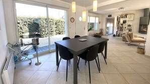 A modern kitchen with a dining area, large windows, and a fireplace. - Contemporary villa 100m from the beach with garden and WIFI (Trégastel)