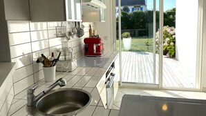 A modern kitchen with a stainless steel sink, white cabinets, and a red appliance. - Contemporary villa 100m from the beach with garden and WIFI (Trégastel)