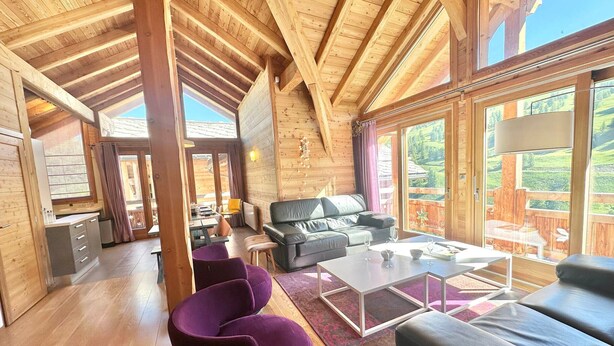 A spacious room with a high wooden ceiling, a black leather sofa, purple chairs, and a dining area with a table and chairs. - Luxury Chalet with Spa & Sauna in Vars (Vars)