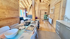 A wooden cabin interior with a dining area, kitchen, and seating space. - Luxury Chalet with Spa & Sauna in Vars (Vars)