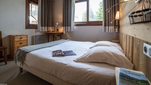 Ein Schlafzimmer mit einem Bett, einem Nachttisch, einer Lampe und einem Fenster mit Vorhängen.