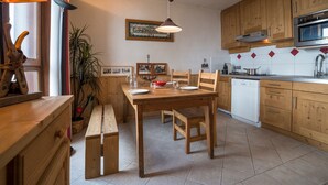 Eine gemütliche Küche mit Holdekor-Schränken, einem Esstisch mit Bänken, einer Pendelleuchte und einer gefliesten Spritzschutzwand.