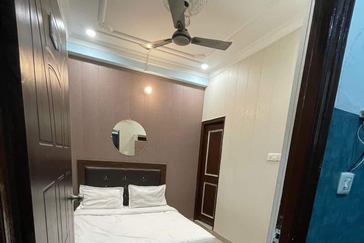 A bedroom with a bed, a ceiling fan, a mirror, and a door.