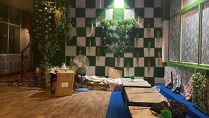 A room with a checkered wall pattern, a ceiling fan, and a blue carpet. - Namoh Stay (Rishikesh)