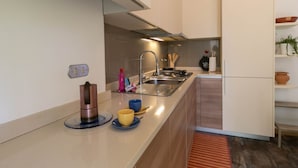 A modern kitchen with a built-in stove, sink, and a small island with a coffee maker and bowls. - Turati Family Apartment (Lecco)