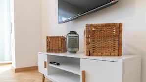 A white TV stand with wicker baskets and a green vase. - Turati Family Apartment (Lecco)