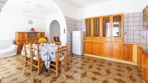Une cuisine de taille réduite avec des meubles de rangement en bois, une table à manger avec des chaises et un réfrigérateur.