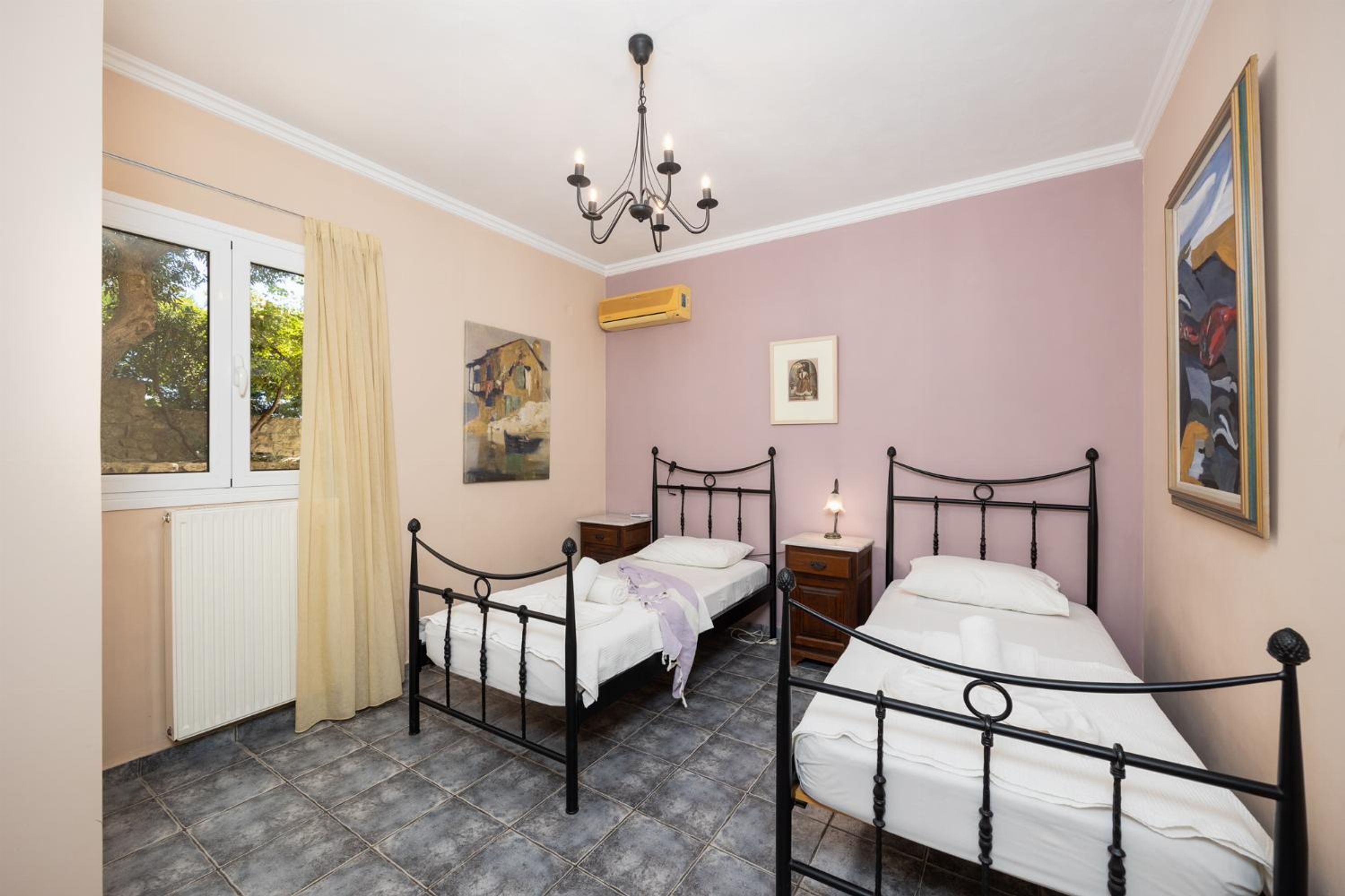 Un dormitorio con dos camas, una araña, una ventana con vistas y obras de arte en las paredes.