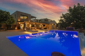 Uma casa moderna com piscina, área de estar externa e espaço de bar.