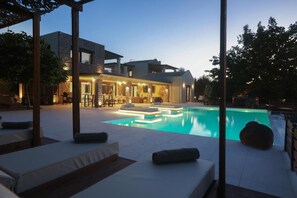 Uma casa moderna com piscina, área de estar externa e um pátio bem iluminado.