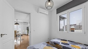 Un dormitorio con dos camas, una ventana y una puerta que da a un baño.