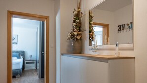 A modern bathroom with a large mirror, a sink, and a decorative plant.