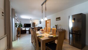 A modern kitchen with a dining area, stainless steel appliances, and a flat-screen TV.