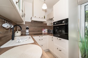 A modern kitchen with white cabinets, a built-in oven, and a coffee machine. - Villa Jadran in Donje Ra Tane (Sveti Filip i Jakov)