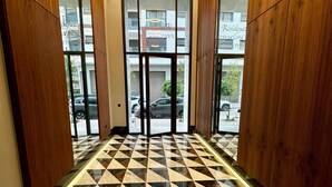 A hotel lobby with a checkered floor pattern, wooden paneling, and a modern chandelier. - StayInn - Pavillon Les Princesses (Casablanca)