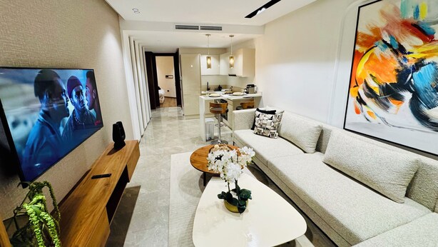 A modern living room with a flat-screen TV, a sofa, a coffee table, and a painting on the wall. - StayInn - Pavillon Les Princesses (Casablanca)