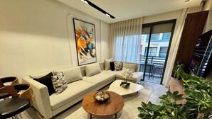 A modern living room with a sectional sofa, a round coffee table, and a bar stool. - StayInn - Pavillon Les Princesses (Casablanca)