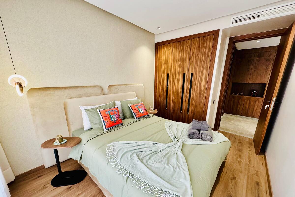 Une chambre à coucher bien rangée, avec un lit, une table de chevet et une armoire.