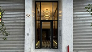 A modern building entrance with a glass door, a number "38" on the wall, and a patterned floor. - StayInn - Pavillon Les Princesses (Casablanca)