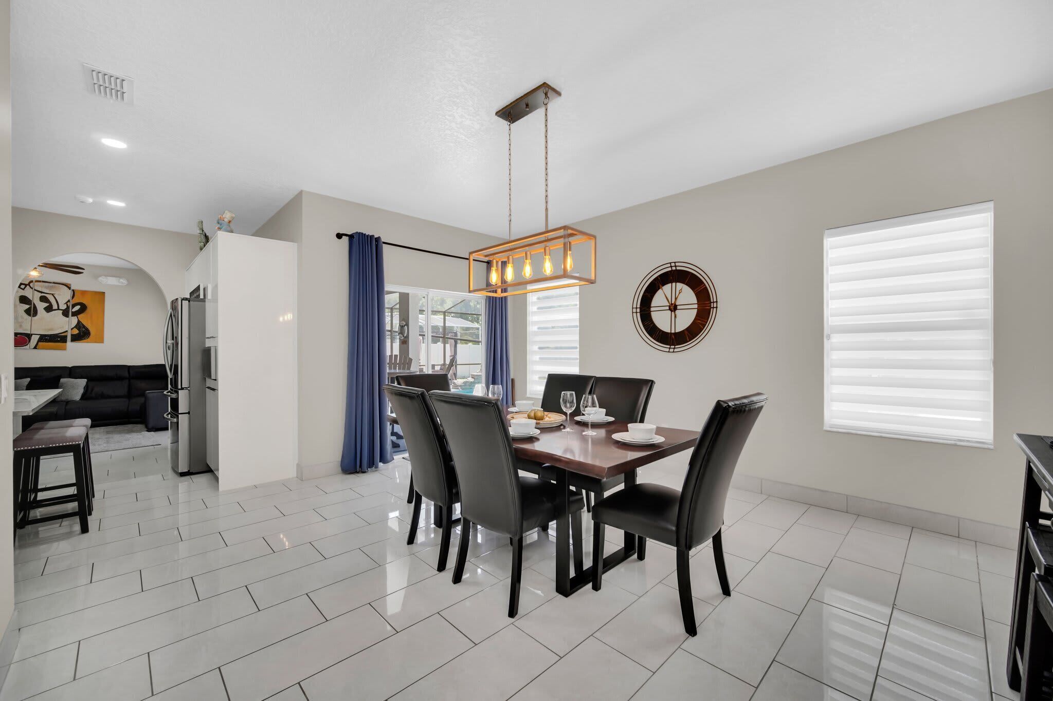 A modern dining area with a rectangular table, black chairs, and a hanging light fixture.