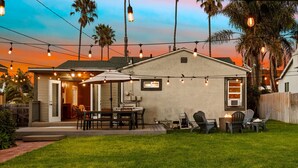 A backyard with a patio area, outdoor seating, and string lights.