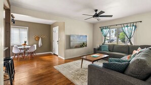 A living room with a sofa, coffee table, and a dining area with chairs and a table.