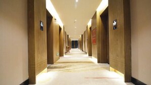 Un pasillo largo y estrecho con paredes de madera y suelo de mármol, que conduce a una puerta al final.