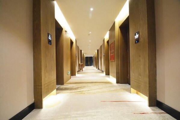 A long, narrow hallway with wooden walls and a marble floor, leading to a door at the end. - Xiyue Hotel (Zhengzhou east station store) (Zhengzhou)