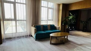 Una sala de estar moderna con un sofá, una mesa de centro y ventanas grandes con cortinas de gasa.