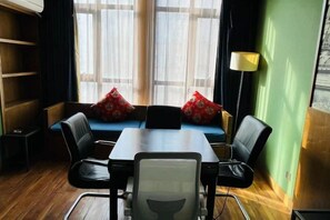 A room with a dining table, chairs, a sofa with red cushions, a floor lamp, and a bookshelf. - Xiyue Hotel (Zhengzhou east station store) (Zhengzhou)