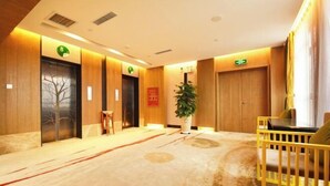 A hotel lobby with wooden paneling, a reception desk, a plant, and a yellow seating area.