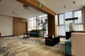 A hotel lobby with a reception desk, seating area, large windows, and a statue. - Xiyue Hotel (Zhengzhou east station store) (Zhengzhou)