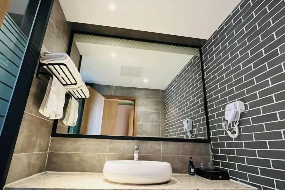 A modern bathroom with a round sink, a mirror, and a towel rack.