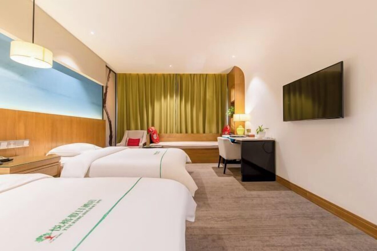 Une chambre d’hôtel avec deux lits, un bureau, une chaise, une télévision et une fenêtre avec des rideaux.