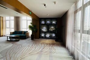A hotel lobby with a sofa, a coffee table, a potted plant, and a display of decorative items. - Xiyue Hotel (Zhengzhou east station store) (Zhengzhou)