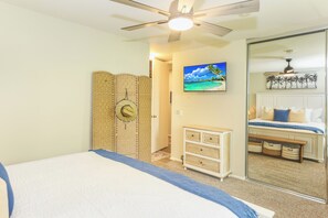 A bedroom with a bed, a ceiling fan, a TV, a wardrobe, and a mirror. - NCV C4 Beautiful beachfront cottage, all new furnishings w/ Stunning Ocean views (Oceanside)