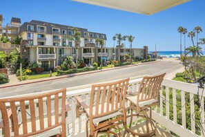 A hotel with a balcony overlooking a street and a beach. - NCV C4 Beautiful beachfront cottage, all new furnishings w/ Stunning Ocean views (Oceanside)