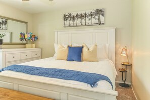 A bedroom with a bed, a nightstand, a lamp, and a painting on the wall.