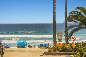 A beach with tents, palm trees, and clear blue water. - NCV C4 Beautiful beachfront cottage, all new furnishings w/ Stunning Ocean views (Oceanside)