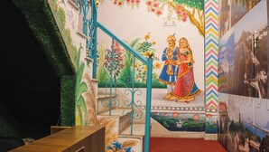 A reception area with a staircase leading to a lower level, decorated with murals and a metal railing. - Hostel Funky Bunky  (Udaipur)
